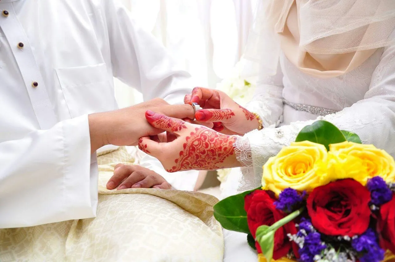 A wedding ring exchange beside a colorful bouquet